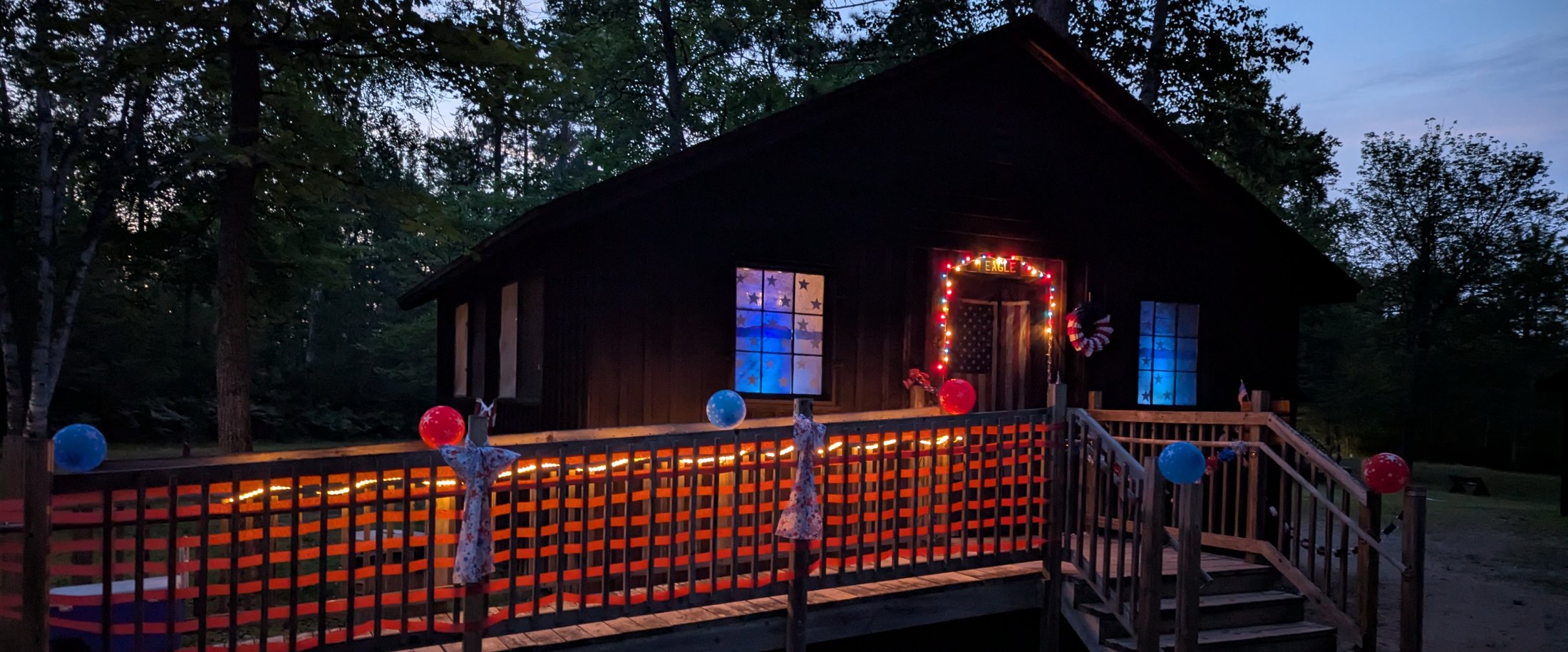 Cabin porch at dusk, decorated with lights and balloons for Christmas in July